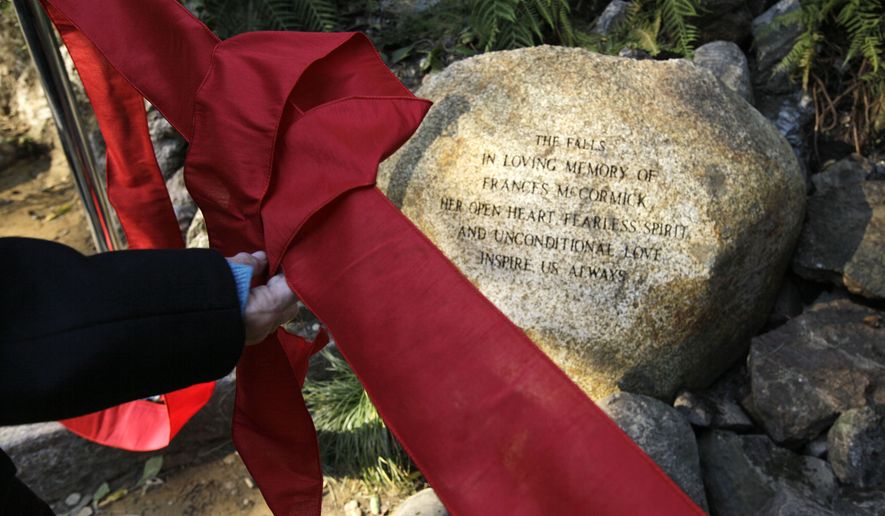 Carlin Holden places a red ribbon beside "The Falls" which were recently restored at the National AIDS Memorial Grove on World AIDS Day in San Francisco. (AP Photo/Eric Risberg)