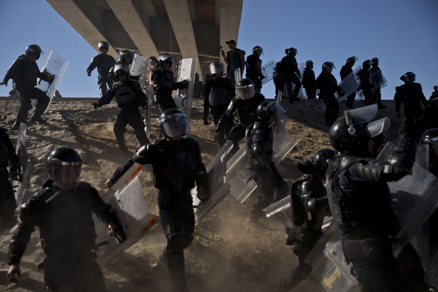 Mexican police run as they try to keep migrants from getting past the Chaparral border crossing in Tijuana, Mexico, Sunday, Nov. 25, 2018, near San Ysidro, California. The mayor of Tijuana has declared a humanitarian crisis in his border city and says that he has asked the United Nations for aid to deal with the approximately 5,000 Central American migrants who have arrived in the city. (AP Photo/Ramon Espinosa)