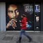A woman walks past a mural depicting reggae music icon Bob Marley painted on the rolling shutter of a Tobacconist shop in Rome, Thursday, Nov. 28, 2018. (AP Photo/Gregorio Borgia)