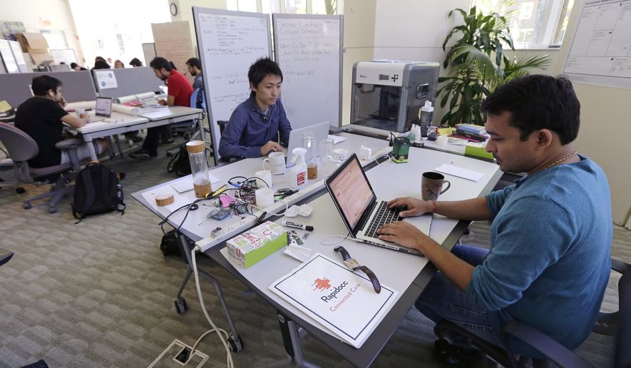 In this Thursday, June 30, 2016 photo, Babson College graduate school alumnus Abhinav Sureka, of Mumbai, India, right, types in his work space at the college in Wellesley, Mass. Some U.S. colleges are starting programs to help their alumni get visas through what critics say is a legal loophole. Foreign grads who want to stay and start a business typically apply for one of the 85,000 H-1B visas that the U.S. gives out each year. But college employees are exempt from that cap, so schools like UMass, Babson and CUNY have launched programs to hire alumni and foreign entrepreneurs and help them grow their businesses here. (AP Photo/Charles Krupa) **FILE**
