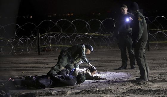 A U.S. Border Patrol agent pats down Honduran migrants after they crossed onto U.S territory from Tijuana, Mexico, Friday, Nov. 30, 2018. Thousands of migrants who traveled via a caravan members want to seek asylum in the U.S. but may have to wait months because the U.S. government only processes about 100 of those cases a day at the San Ysidro border crossing in San Diego. (AP Photo/Felix Marquez)