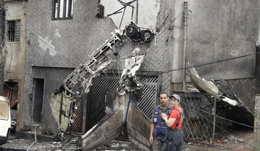 Firefighters and police work at the site where a small plane crashed into a residential area of Sao Paulo, Brazil, Friday, Nov. 30, 2018. A small single-engine plane crashed leaving at least two people dead and a dozen injured, according to firefighters. (AP Photo/Andre Penner)