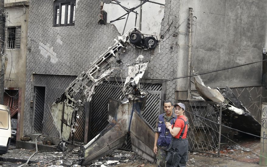 Firefighters and police work at the site where a small plane crashed into a residential area of Sao Paulo, Brazil, Friday, Nov. 30, 2018. A small single-engine plane crashed leaving at least two people dead and a dozen injured, according to firefighters. (AP Photo/Andre Penner)