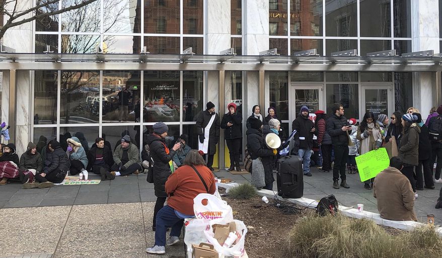 Supporters of Nelson Pinos, facing deportation, block the front doors of the federal building, Friday, Nov. 30, 2018, in Hartford, Conn. They are demanding that Immigration and Customs Enforcement allow Pinos, of Ecuador, to go home to his family in time for the holidays. He was ordered to leave the U.S. a few weeks before Christmas 2017. He instead sought sanctuary in a New Haven church. (AP Photo/Dave Collins)