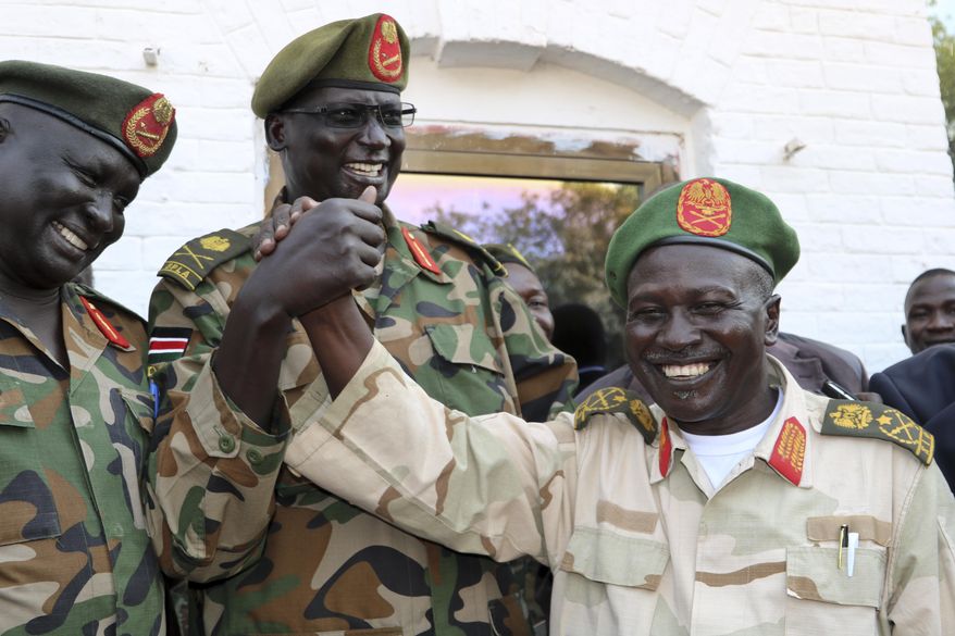 In this photo taken Thursday, Nov. 22, 2018, a South Sudan armed opposition commander Ashab Khamis, right, and a government army Gen. Keer Kiir Keer, center-left, shake hands after high level talks where both sides exchanged accusations of violating the peace agreement, in Wau, South Sudan. The Associated Press witnessed the first meeting between the Wau region leaders of South Sudan's army and armed opposition since a groundbreaking peace deal, and the country's peace rests on whether the opposing sides can put a vicious past behind. (AP Photo/Sam Mednick)