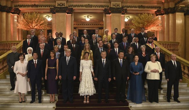 In this photo released by the press office of the G20 Summit, leaders and their partners pose for a group photo prior to a gala dinner at the Colon Theater in Buenos Aires, Argentina, Friday, Nov. 30, 2018. Leaders from the Group of 20 industrialized nations are meeting in Buenos Aires for two days starting today. (G20 Press Office via AP)