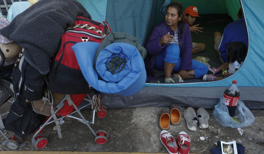 A migrant family with their belongings packed waits in their tent on the street for buses to arrive to carry them to a new shelter, in Tijuana, Mexico, Saturday, Dec. 1, 2018. By Saturday afternoon, most of the thousands of migrants who had been camped out at the sports complex had agreed to move to the new, more distant shelter. Others decided to try their luck camping in the street near the former shelter or look for their own accommodation.(AP Photo/Rebecca Blackwell)