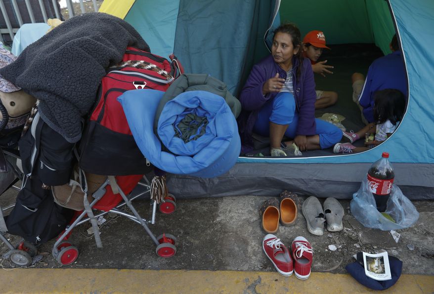 A migrant family with their belongings packed waits in their tent on the street for buses to arrive to carry them to a new shelter, in Tijuana, Mexico, Saturday, Dec. 1, 2018. By Saturday afternoon, most of the thousands of migrants who had been camped out at the sports complex had agreed to move to the new, more distant shelter. Others decided to try their luck camping in the street near the former shelter or look for their own accommodation.(AP Photo/Rebecca Blackwell)