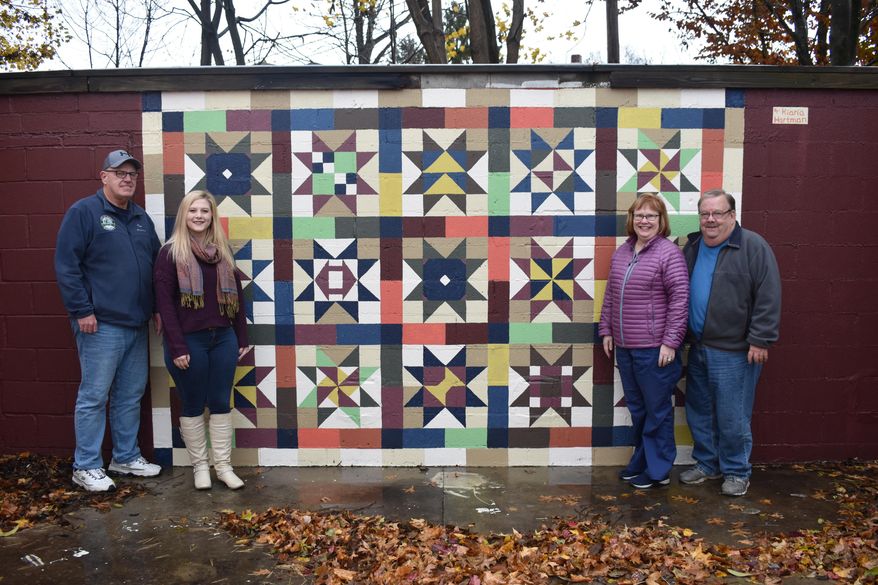 In this recent photo, from left, Elkins Elkins Mayor Van Broughton, artist Kiana Hartman. Deborah and Jeff Welshonce, Space-ial Places Storage Units owners, pose by a mural Hartman painted in Elkins, W.Va. Hartman spent the better part of a year creating the quilt mural on the wall of Space-ial Places Storage Units. (Tim MacVean/Daily Inter-Mountain via AP)