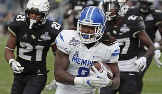 Memphis running back Darrell Henderson, center, runs past Central Florida defensive backs Rashard Causey (21) and  Richie Grant, right, for a 12-yard touchdown run during the first half of the American Athletic Conference championship NCAA college football game, Saturday, Dec. 1, 2018, in Orlando, Fla. (AP Photo/John Raoux)