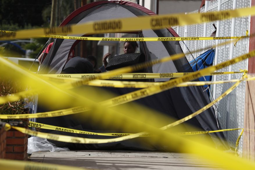 A woman packs belongings in a tent on the sidewalk, next to where one property owner had strung caution tape to prevent migrants from camping, outside a sports complex shelter which authorities were trying to close, in Tijuana, Mexico, Saturday, Dec. 1, 2018. By Saturday afternoon, most of the thousands of migrants who had been camped out at the sports complex had agreed to move to the new, more distant shelter. Others decided to try their luck camping in the street near the former shelter or look for their own accommodation.(AP Photo/Rebecca Blackwell)