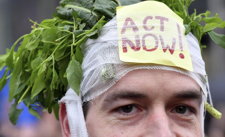 A demonstrator wears a headband stuffed with greens and a sign which reads 'act now' during a 'Claim the Climate' march in Brussels, Sunday, Dec. 2, 2018. The climate change conference, COP24, will take place in Poland from Dec. 2-14. (AP Photo/Geert Vanden Wijngaert)