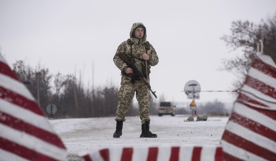 A Ukrainian border guard stands ready at the border from Russia to Ukrainian side of the Ukraine - Russia border in Milove town, eastern Ukraine, Sunday, Dec. 2, 2018. On a map, Chertkovo and Milove are one village, crossed by Friendship of Peoples Street which got its name under the Soviet Union and on the streets in both places, people speak a mix of Russian and Ukrainian without turning choice of language into a political statement. (AP Photo/Evgeniy Maloletka)
