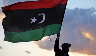 A Libyan waves the national flag during commemorations to mark the second anniversary of the revolution that ousted Moammar Gadhafi in Benghazi, Libya, Friday, Feb, 15, 2013. (AP Photo/Mohammad Hannon)