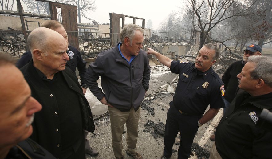 FILE - In a Nov. 14, 2018 file photo, Scott Upton, right, the chief of the Northern Region for the California Department of Forestry and Fire Protection briefs California Gov. Jerry Brown, second from left, Federal Emergency Management Agency Director Brock Long, third from left, and U.S. Secretary of the Interior Ryan Zinke, third from left, and Mark Ghilarducci, director of the Governor's Office of Emergency Services, right, look at the remains of Paradise Elementary school in Paradise, Calif. Monday Dec. 3 marks a return to school and some semblance of routine for thousands of children who lost their homes in the wildfire. (AP Photo/Rich Pedroncelli, File)