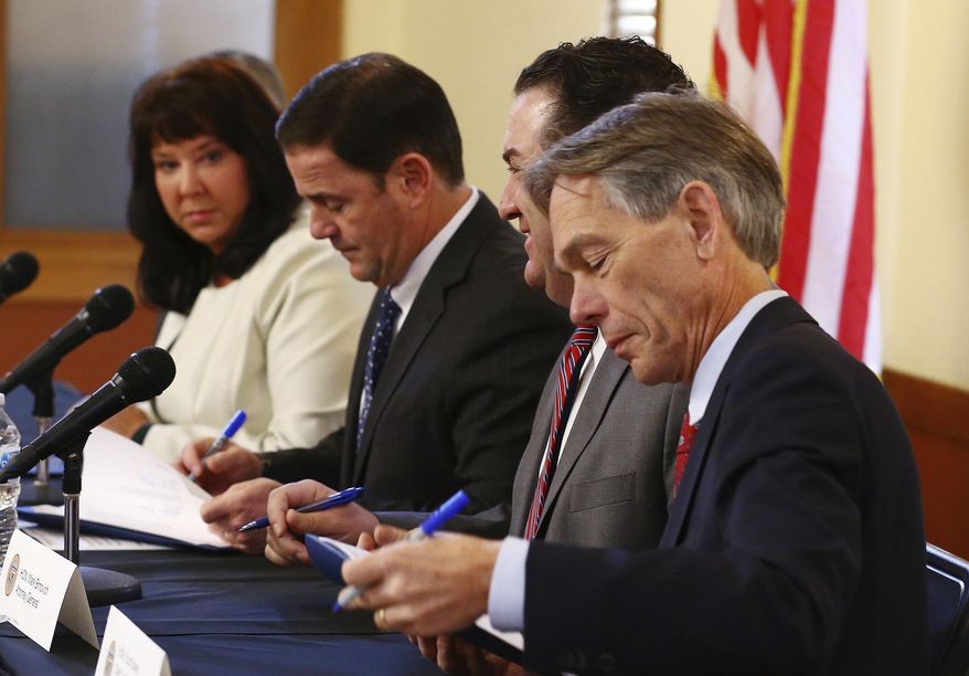 From left to right, Arizona Secretary of State Michele Reagan, Arizona Republican Gov. Doug Ducey, Arizona Attorney General Mark Brnovich, and Arizona Supreme Court Chief Justice Scott Bales add their signatures at the signing of the official election canvass Monday, Dec. 3, 2018, in Phoenix. (AP Photo/Ross D. Franklin)