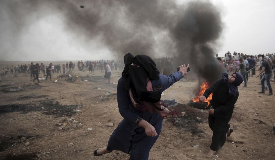 Palestinian women hurl stones at Israeli troops during a protest at the Gaza Strip&#x27;s border with Israel on May 4, 2018. (AP Photo/ Khalil Hamra)