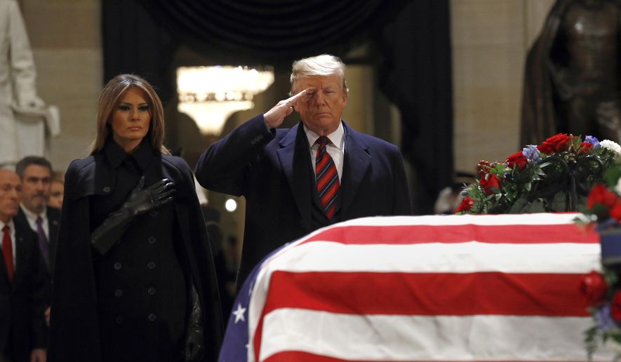 President Donald Trump salutes alongside first lady Melania Trump in front of the flag-draped casket of former President George H.W. Bush in the Capitol Rotunda in Washington, Monday, Dec. 3, 2018. (AP Photo/Patrick Semansky)