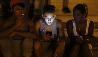 FILE - In this July 1, 2015 file photo, youths use a password protected wifi network coming from a five star hotel to surf the Internet on their smart phones in downtown Havana, Cuba. Cuba&#39;s government announced on Tuesday, Dec. 4, 2018 that its citizens will be offered full internet access on mobile phones starting Thursday, Dec. 6, becoming one of the last nations to do so. (AP Photo/Desmond Boylan, File)