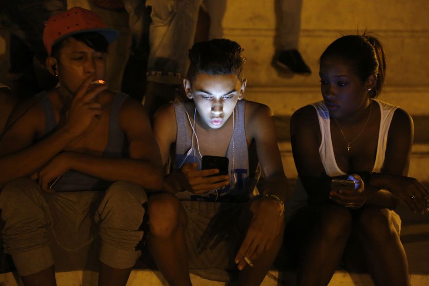 FILE - In this July 1, 2015 file photo, youths use a password protected wifi network coming from a five star hotel to surf the Internet on their smart phones in downtown Havana, Cuba. Cuba&#39;s government announced on Tuesday, Dec. 4, 2018 that its citizens will be offered full internet access on mobile phones starting Thursday, Dec. 6, becoming one of the last nations to do so. (AP Photo/Desmond Boylan, File)