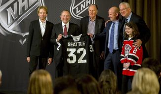 NHL commissioner Gary Bettman, center left, holds a jersey after the NHL Board of Governors announced Seattle as the league&#39;s 32nd franchise, Tuesday, Dec. 4, 2018, in Sea Island Ga.. Joining Bettman, from left to right, is Jerry Bruckheimer, David Bonderman, David Wright, Tod Leiweke and Washington Wild youth hockey player Jaina Goscinski. (AP Photo/Stephen B. Morton)