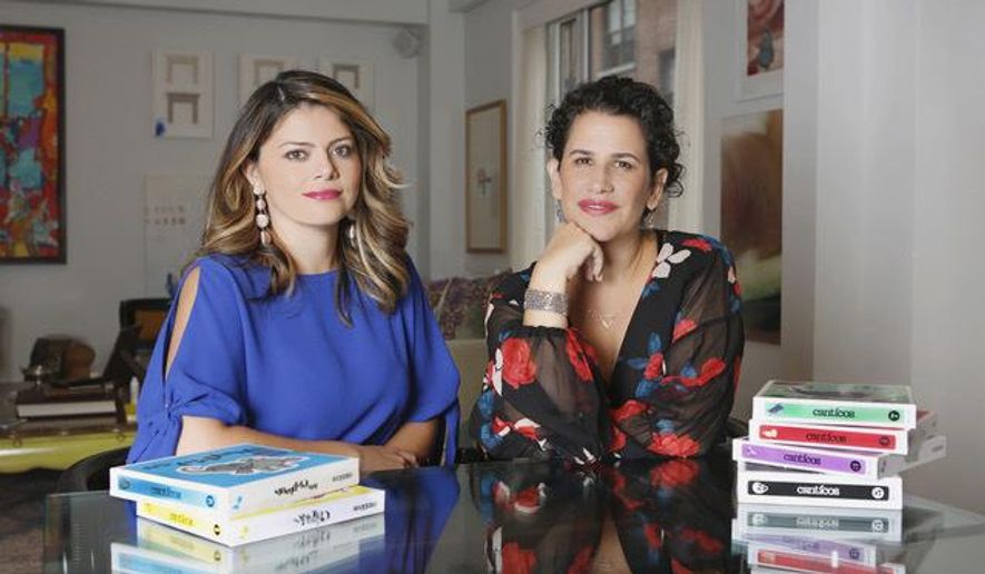 In this undated photo provided by Creation Studios, Nuria Santamaria Wolfe, left, and Susie Jaramillo, right, co-founders of family-owned entertainment company Encantos Media Studios, pose for a photo with their series of bilingual nursery rhyme books, Canticos. (Lara Alcantara/Creation Studios via AP)