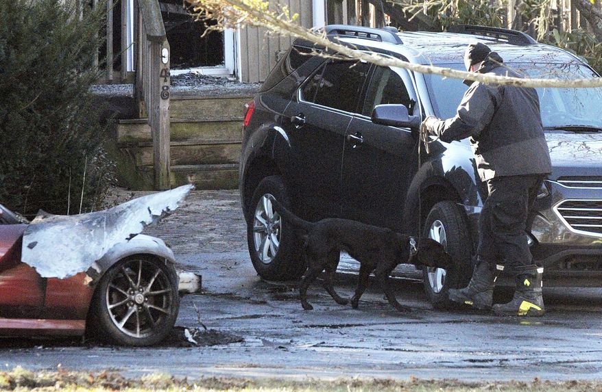 Investigators examine burned vehicles in front of a burned home in Dudley, Mass., Tuesday, Dec. 4, 2018. Authorities say one person has been found dead at the central Massachusetts property where several fires were reported. (Rick Cinclair/Worcester Telegram & Gazette via AP)