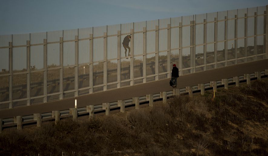 In a photo taken from the Tijuana, Mexico, side of the border, two immigrants on U.S. soil try to jump the second wall before border police arrived and arrested them, Sunday, Dec. 2, 2018. Thousands of migrants who traveled via caravan are seeking asylum in the U.S., but face a decision between waiting months or crossing illegally, because the U.S. government only processes a limited number of cases a day at the San Ysidro border crossing in San Diego. (AP Photo/Ramon Espinosa)