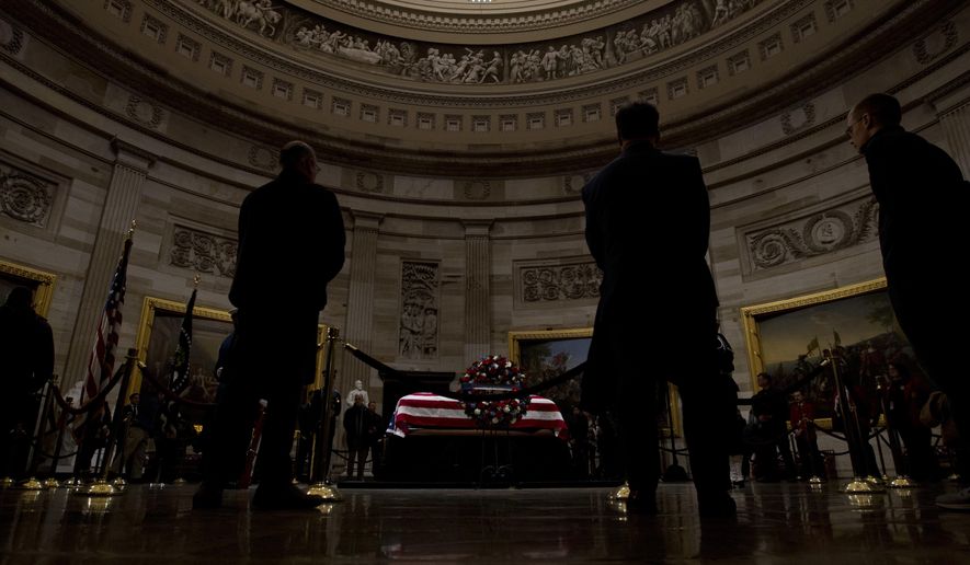 Visitors pay their respects at the flag-draped casket of former President George H.W. Bush, as he lies in state in the Capitol Rotunda in Washington, Wednesday, Dec. 5, 2018. (AP Photo/Jose Luis Magana)