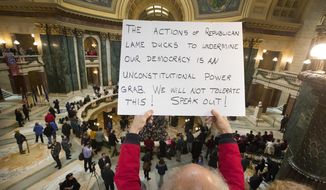 People protest the legislature&#x27;s extraordinary session during the official Christmas tree lighting ceremony at the Capitol in Madison, Wis., Tuesday, Dec. 4, 2018. Demonstrators booed outgoing Wisconsin Gov. Scott Walker on Tuesday during the Christmas tree-lighting ceremony, at times drowning out a high school choir with their own songs in protest of a Republican effort to gut the powers of his Democratic successor. (Mark Hoffman/Milwaukee Journal-Sentinel via AP)