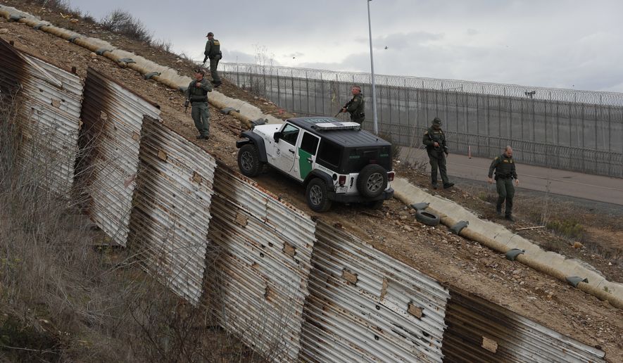 U.S. border patrol agents standing in San Ysidro, California leave after responding to at least two men on the Mexican side of the U.S. border wall, one with his face covered and another holding rocks, in Tijuana, Mexico, Thursday, Dec. 6, 2018. The incident diffused soon after and the agents left. (AP Photo/Rebecca Blackwell)