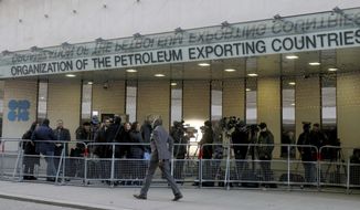 People stand in front of the headquarters of the Organization of the Petroleum Exporting Countries, OPEC, in Vienna, Austria, Wednesday, Dec. 5, 2018. (AP Photo/Ronald Zak)