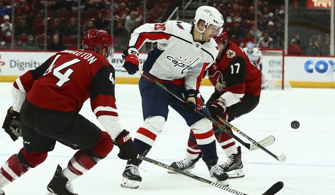 Washington Capitals center Lars Eller (20) tries to control the puck between Arizona Coyotes defenseman Kevin Connauton (44) and center Alex Galchenyuk (17) during the first period of an NHL hockey game Thursday, Dec. 6, 2018, in Glendale, Ariz. (AP Photo/Ross D. Franklin)