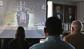 Attendees to George H.W. Bush&#39;s funeral viewing at the Presidential Museum and Leadership Library in Odessa, Texas, look on as a military honor guard delivers Bush&#39;s casket to the Washington National Cathedral in Washington, Wednesday, Dec. 5, 2018. (Jacob Ford/Odessa American via AP)