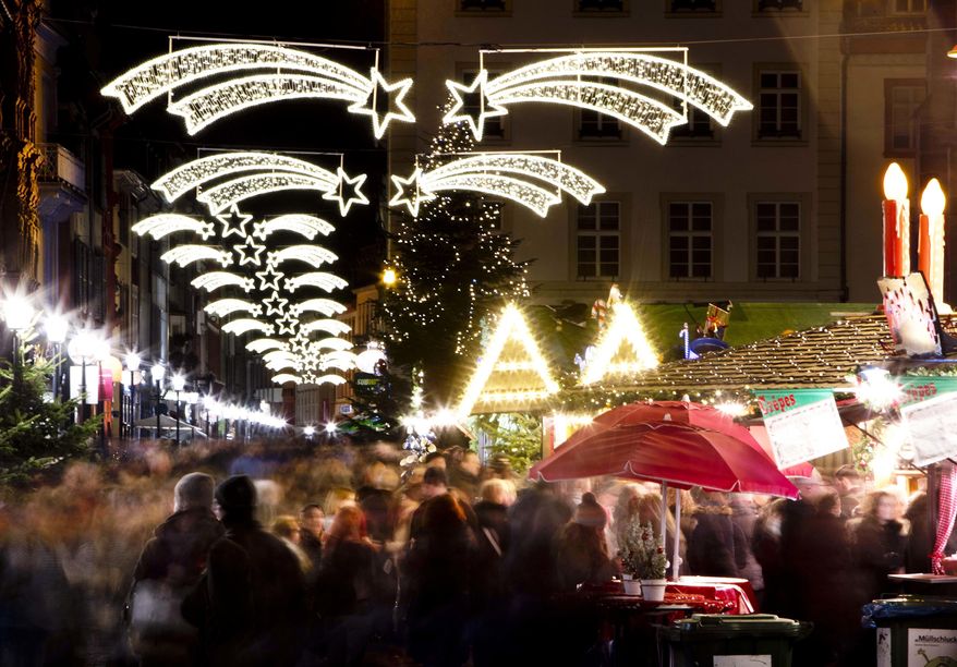 In this Tuesday, Dec. 4, 2018 photo people pay a visit to the traditional Christmas market in Heidelberg, Germany. The Christmas market In the Old Town of Heidelberg underneath the famous castle is one of most picturesque christmas markets in southern Germany. (AP Photo/Michael Probst)