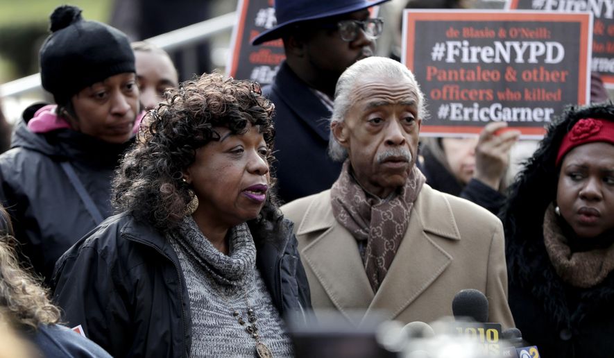 Gwen Carr, center, mother of Eric Garner, stands with Rev. Al Sharpton, right, during a news conference outside of New York Police headquarters, Thursday, Dec. 6, 2018, in New York. Daniel Pantaleo, a New York City police officer accused in the 2014 chokehold death of Garner, an unarmed black man, will face a disciplinary trial in May. (AP Photo/Julio Cortez)