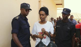 FILE - In this Friday, Oct. 6, 2017 file photo, former Rwanda presidential candidate Diane Rwigara is escorted by policemen to a court where she denied charges of insurrection and forgery that she says are linked to her criticism of the government&#39;s human rights record. As she waits for a judge to pronounce her fate on Thursday, Dec. 6, 2018, the Rwandan opposition leader accused of inciting insurrection and forgery says no amount of pressure will silence her. (AP Photo, File)