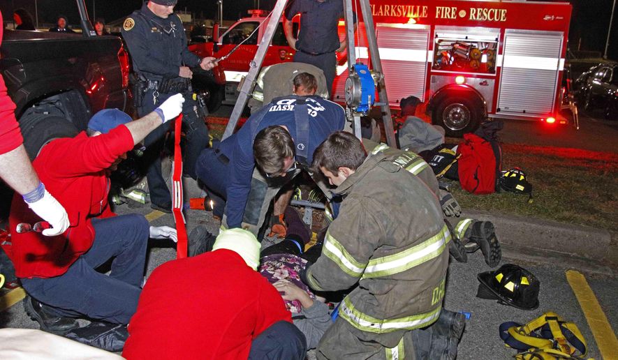 In this Thursday, Dec. 6, 2018 photo, released by the Clarksville Police Department, emergency responders rescue a woman and her baby trapped in a storm drain in a parking lot in Clarksville, Tenn. Police spokesman Jim Knoll says the woman was walking through the parking lot carrying her baby when the storm grate she went across collapsed. (Jim Knoll/Clarksville Police Department via AP)