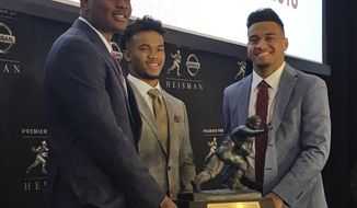 Heisman Trophy finalists, from left, Dwayne Haskins, from Ohio State, Kyler Murray, of Oklahoma, and Tua Tagovailoa, from Alabama, pose with the Heisman Trophy at the New York Stock Exchange, Friday, Dec. 7, 2018, in New York. (AP Photo/Ralph Russo)