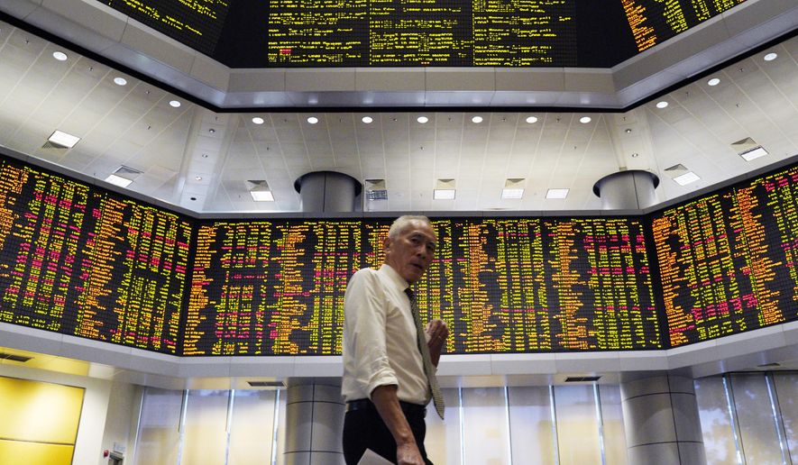 A visitor walks in front of private stock trading boards at a private stock market gallery in Kuala Lumpur, Malaysia, Friday, Dec. 7, 2018. Asian shares were mostly higher Friday after gains on Wall Street but investors continued to watch for news about U.S.-China trade friction. (AP Photo/Yam G-Jun)