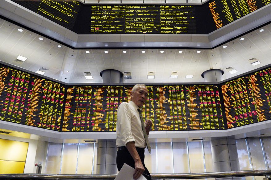 A visitor walks in front of private stock trading boards at a private stock market gallery in Kuala Lumpur, Malaysia, Friday, Dec. 7, 2018. Asian shares were mostly higher Friday after gains on Wall Street but investors continued to watch for news about U.S.-China trade friction. (AP Photo/Yam G-Jun)