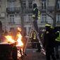 A demonstrator stands on a stepladder during clashes Saturday, Dec. 8, 2018 in Paris. Crowds of yellow-vested protesters angry at President Emmanuel Macron and France&#39;s high taxes tried to converge on the presidential palace Saturday, some scuffling with police firing tear gas, amid exceptional security measures aimed at preventing a repeat of last week&#39;s rioting. (AP Photo/Rafael Yaghobzadeh)