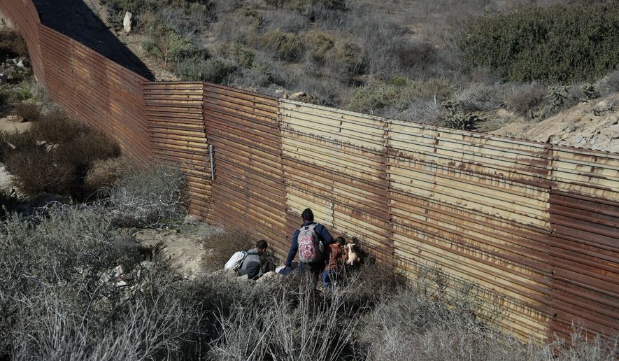 Migrant family members move into a hole to cross under the U.S. border wall, aided by two local guides, in Tijuana, Mexico, Sunday, Dec. 9, 2018. Discouraged by the long wait to apply for asylum through official ports of entry, many Central American migrants from recent caravans are choosing to cross the U.S. border wall illegally and hand themselves in to Border Patrol agents to request asylum. (AP Photo/Rebecca Blackwell)