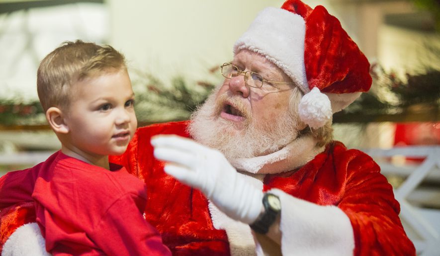 In this Saturday, Dec. 1, 2018 photo, Larry Bennett, playing Santa Claus, talks with the first kid in line Weston Stapp during the Breakfast with Santa on at the Longview Museum of Fine Art in Longview, Texas.. (Courtney Case/The News-Journal via AP)