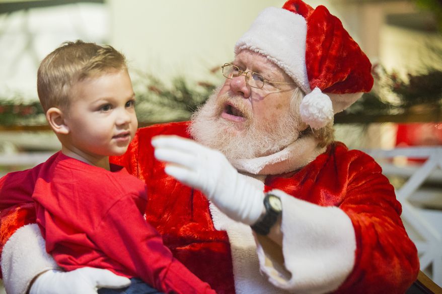 In this Saturday, Dec. 1, 2018 photo, Larry Bennett, playing Santa Claus, talks with the first kid in line Weston Stapp during the Breakfast with Santa on at the Longview Museum of Fine Art in Longview, Texas.. (Courtney Case/The News-Journal via AP)