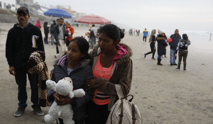 A Honduran migrant and her daughter stand on the beach looking toward the U.S. border wall, moments before suddenly squeezing through a gap and pushing through fencing to emerge on U.S. soil, in Tijuana, Mexico, Sunday, Dec. 9, 2018. Discouraged by the long wait to apply for asylum through official ports of entry, many Central American migrants from recent caravans are choosing to cross the U.S. border wall illegally and hand themselves in to Border Patrol agents to request asylum. (AP Photo/Rebecca Blackwell)
