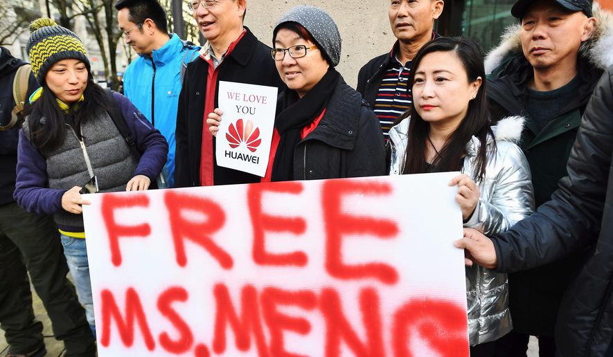 People hold a sign at a Vancouver, British Columbia, courthouse prior to the bail hearing for Meng Wanzhou, Huawei&#39;s chief financial officer on Monday. (Associated Press)