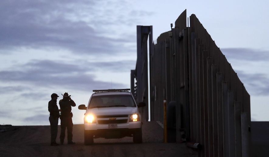In this Wednesday, Nov. 21, 2018, file photo, United States Border Patrol agents stand by a vehicle near one of the border walls separating Tijuana, Mexico and San Diego, in San Diego. (AP Photo/Gregory Bull, File)