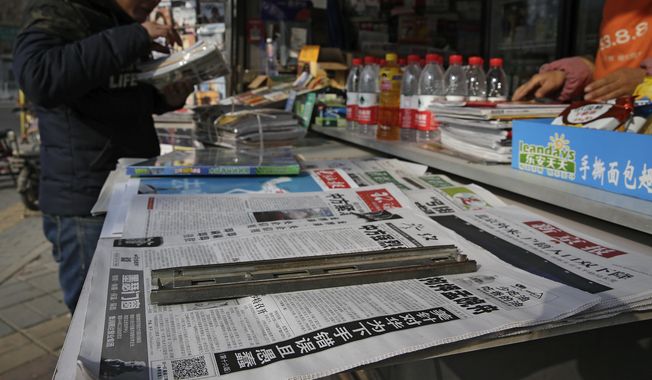 A man arranges magazines near newspapers with the headlines of China outcry against the U.S. on the detention of Huawei&#x27;s chief financial officer, Meng Wanzhou. (Associated Press/File)