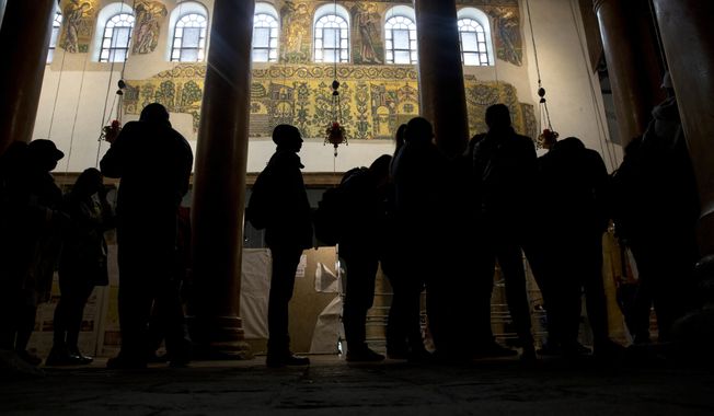 In this Thursday, Dec. 6, 2018 photo, visitors stand bellow a renovated part of a fresco inside the Church of the Nativity, built atop the site where Christians believe Jesus Christ was born, in the West Bank City of Bethlehem. City officials are optimistic that the renovated church will help add to a recent tourism boom and give a boost to the shrinking local Christian population. (AP Photo/Majdi Mohammed)
